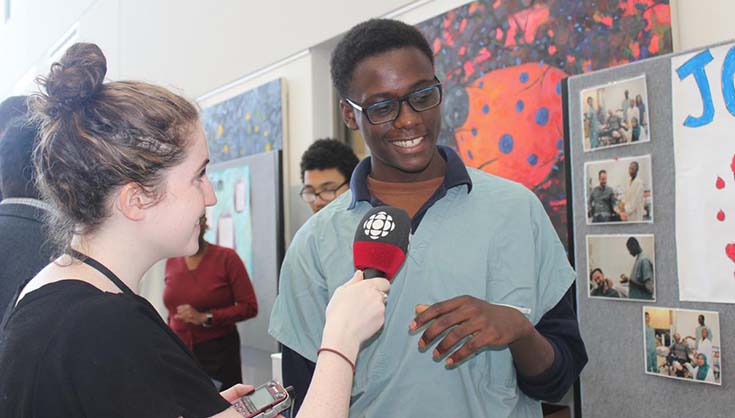 Rayan Primus from John Grant High School discusses his wound project with a CBC reporter Rayan Primus from John Grant High School discusses his wound project with a CBC reporter